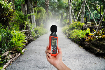 hand holding a digital sound levelin the park,Noise pollution prevention concept 