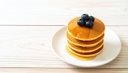 Stack of blueberry pancakes dripping with syrup on a white plate, Delicious breakfast pancakes topped with blueberries and syrup on a wooden table
