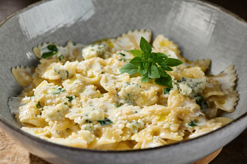 Farfalle quattro formaggi in bright rustic lighting, overhead view with creamy cheese sauce and fresh herb garnish