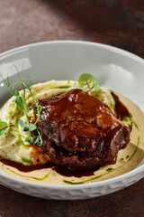 Braised beef cheek with mashed potatoes in demi-glace, moody lighting, overhead composition