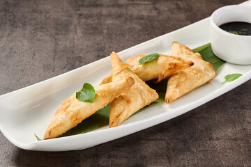 Crab turnovers on a rustic background, moody lighting, overhead composition on a long white plate