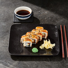 Unagi roll with avocado and salmon, bright lighting, overhead composition, on dark slate