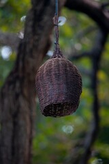 Close-up of a wicker lamp with a blurred garden background