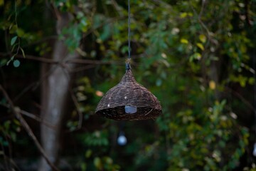Close-up of a wicker lamp with a blurred garden background