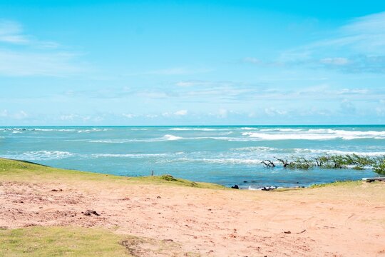 Serene beach scene with gentle waves, clear blue sky, and sandy shore