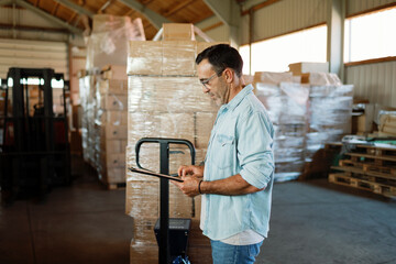 Warehouse manager using digital tablet checking inventory in large distribution center