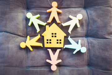 Colorful paper cutout figures arranged in a circle around a house symbol on a soft background,...
