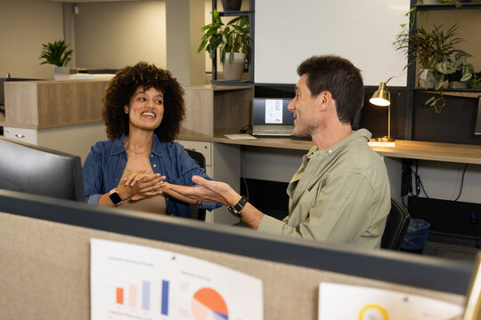 Collaborating Diverse coworkers reviewing data on monitors at office desks, with desk lamp, plants