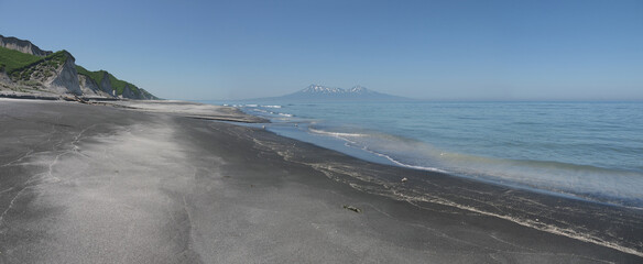 Iturup black sand beach with river mouth and volcano in background