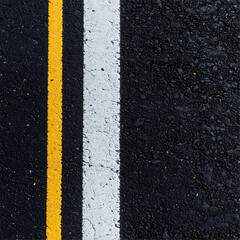 Fototapeta premium Close-up view of asphalt road surface with yellow and white lane markings.