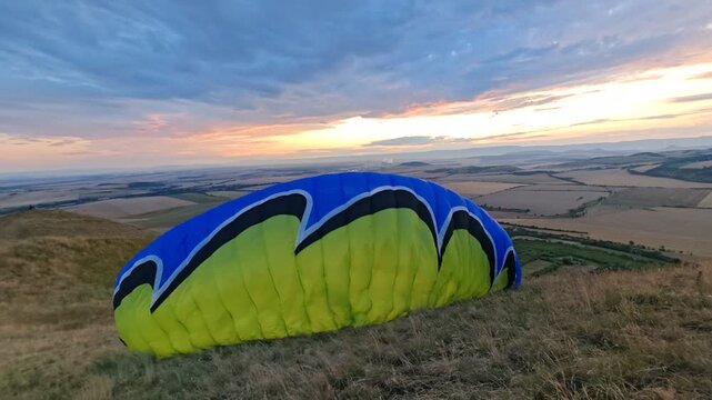 Paragliding pilot launching with his Paraglider wing from Rana mountain peak near Louny for free flight in clear sky.