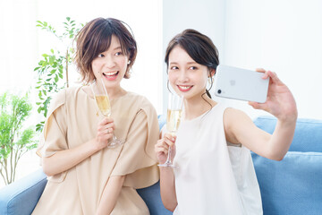 シャンパングラスを手に撮影する女性2人 © TAGSTOCK2