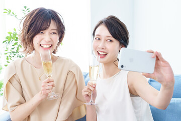シャンパングラスを手に撮影する女性2人 © TAGSTOCK2