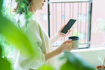 部屋でスマートフォンを手にする女性