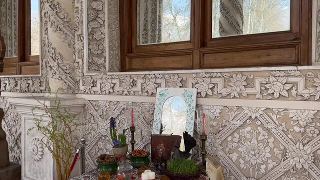 Decorative wall art with white plaster moulding around wooden frame windows Haftsin ritual New Year table mansion terrace stone column garden Iranian palace luxury Nowruz spring festive Tehran Tajrish