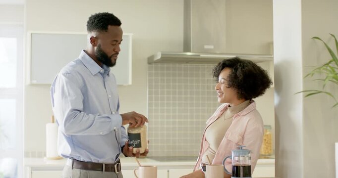 Diverse couple reacting as man lifting sugar jar, adding sugar to sweeten coffee at kitchen island