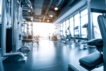 Modern gym interior with exercise equipment and natural light filtering through large windows