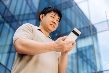 Asian businessman using smartphone in front of office building