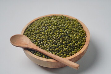 Wooden Bowl Filled with Mung Beans and Wooden Spoon on White Background