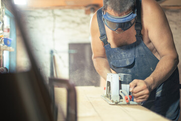 Closeup of joiner working with electric circular saw  for cutting wooden plywood