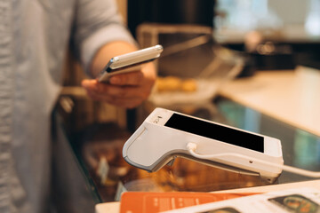 Customer paying contactless with mobile phone at pos terminal
