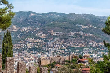 Obraz premium Scenic view of Alanya, Turkey, framed by historic Alanya Castle walls. City architecture and mountains under clear sky highlight the charm of this popular Mediterranean destination