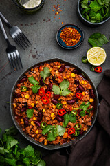 Chili con carne with beef, beans, paprika, corn, cilantro, jalapeno in tomato sauce, in frying pan, rusty green background top view