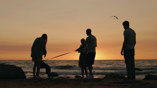 Group of friends with a dog on the beach at sunrise