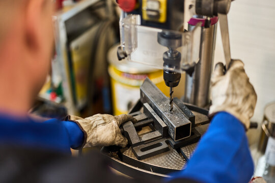 Worker Operating Drill Press to Machine Metal Component in Industrial Workshop - Powered by Adobe