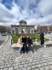 Friends in Historic Plaza: Three companions, united by friendship, find joy amidst the architectural grandeur of a historic plaza. A shared moment of connection and memory-making. Alcalá Madrid spain