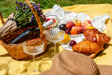 A bright summery picnic setup with fresh fruits, pastries, a floral bouquet, and a wicker basket. Chic glasses and a cozy blanket. Relaxation, enjoying nature, outdoor dining, summer leisure concept