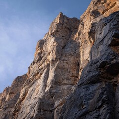 Bouldered cliff face with precise edges under clear morning sky