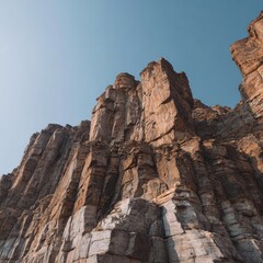 Fototapeta premium Rugged sandstone cliffs with geometric shapes beneath a clear sky