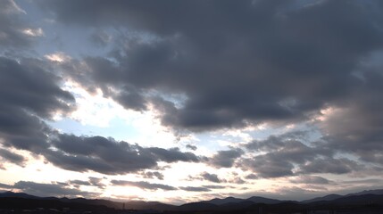 Dramatic cloudscapes at sunset over a distant mountain range.