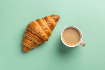 Golden croissant and coffee cup on a mint green background