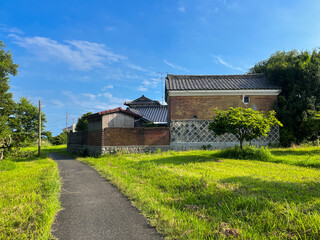 青空と草原に囲まれた日本の伝統的な蔵と田舎道の風景
