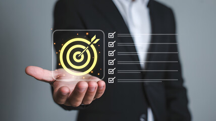 Man in suit holding a digital display with a target and checklist overlay in his open hand