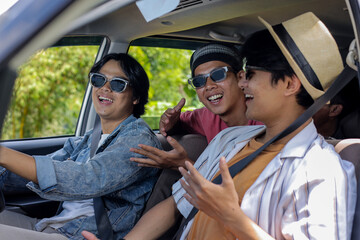 Three Cheerful Young Men Are Having A Great Time On A Road Trip, Chatting Happily While Driving