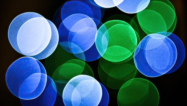 Abstract bokeh lights of vibrant blue and green circles against a dark background