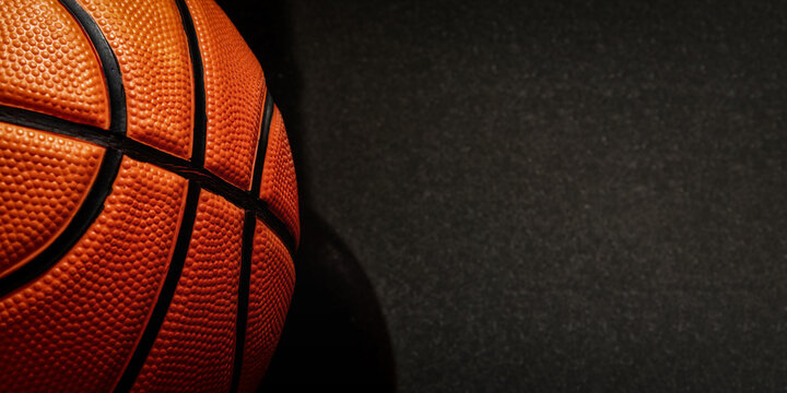A close-up view of a basketball showcases its textured surface and black seams, providing a dynamic sports image. Banner with copy space for text