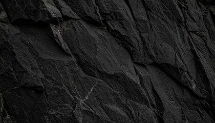 A close-up view of textured black rock surface, showcasing jagged edges and varying shades of dark gray, emphasizing natural geological formations.