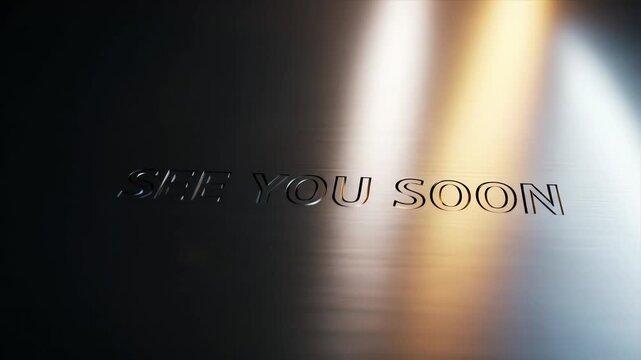 Text "SEE YOU SOON" embossed on a reflective, dark metallic surface, illuminated by light.