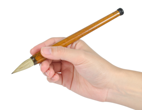 A human hand holds a traditional calligraphy brush with a wooden handle and a tapered natural bristle tip isolated on transparent background. PNG die-cut for advertising