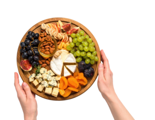 Overhead view of hands holding a wooden board with cheese grapes figs dried apricots and nuts isolated on transparent background. PNG die-cut for advertising