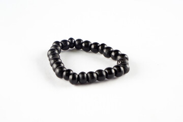 A black beaded bracelet on a plain white background. Traditional piece of jewelry.