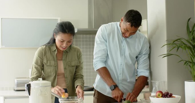 Grabbing egg, diverse couple slicing avocado and whisking eggs in home kitchen preparing breakfast