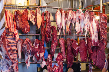 Fresh raw meat hanging at open market stall