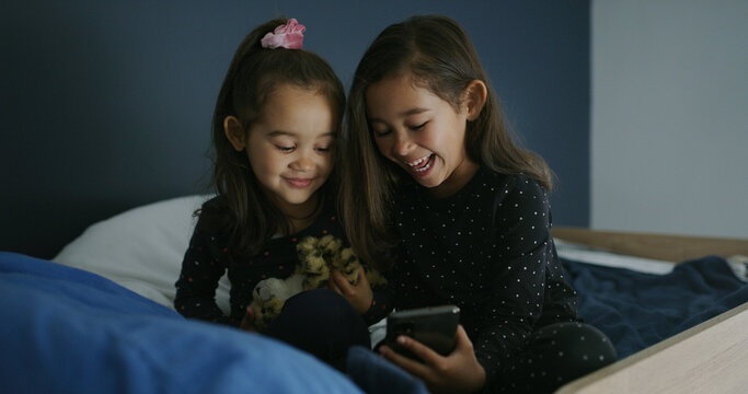 Relax, laughing and phone with kids in bed for streaming, education games and bonding. Learning subscription, meme and sisters or girls in bedroom for family home for child development, joke and web