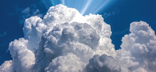 Fluffy white cumulus clouds against a vibrant blue sky, sun rays piercing through