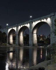 Fototapeta premium Stone arch bridge at night over river